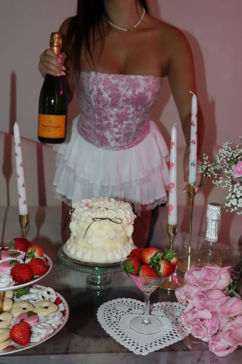 Girl shot from the neck down holding a bottle of champagne. In front of her is a cute birthday party setup with coquettish cakes, candy, strawberries, and candles. Hearts Birthday Party, Light Pink Party Aesthetic, Coquette Bday, Coquette Bday Decor, Coquette Valentines Day, Coquette Birthday Aestethic, Pink And Red Party, Coquette Party Decoration, Croquette Aesthetic Bday