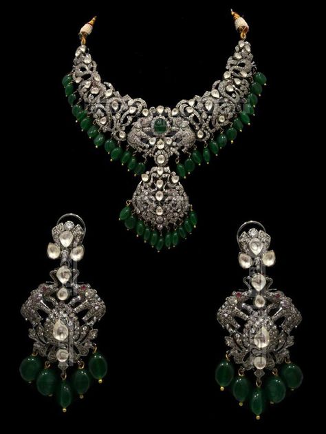 "Israh Victorian Emerald Bridal Set This traditional yet very trendy silver and kundan number is perfect for your wedding attire.This set features a choker style necklace with polki detailing. This Emeralds & Victorian setting stunning necklace set is made of copper+silver alloy with white kundan stones, which are covered in silver foil. The set has a stunning emerald pendant and matching earrings. The whole process is the traditional jadau process of making jewelry. Elevate your style quotient Victorian Style Necklace, Victorian Sets Jewellery, Victorian Antique Jewelry, Victorian Diamond Jewellery, Silver Victorian Jewelry, Vintage Necklace Victorian, Victorian Gold Jewelry, Victorian Polki Jewellery, Victorian Jewelry Indian