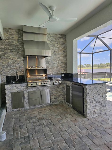 The components listed below are built into this L-shape outdoor kitchen (9’3” in front of the wall with the rough-in & support pillar, and coming out 7’0” away from the wall with the rough-in): Under mount sink with high-arc faucet with soap dispenser installed Single vertical door (under sink) – https://fortmyersprobarbecuegrills.com/product/blaze-single-access-vertical-door-20-x-14/ Tradewind 36” Hood –… Read more » Outdoor Kitchen Backsplash Ideas, L Shaped Outdoor Kitchen, Stacked Stone Outdoor Kitchen, Under Mount Sink, Bbq Grill Island, Pool Oasis, Kitchen Shapes, Silver Travertine, Kitchen Construction