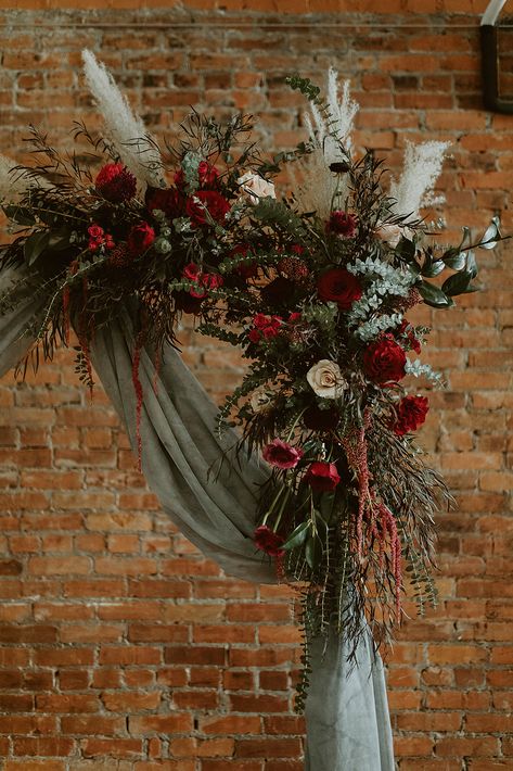 Sage Green December Wedding, Christmas Garland Wedding Arch, Forest Green And Dark Red Wedding, Wedding Arch Ideas Christmas, Christmas Wreath Arch Wedding, Jewel Tone Flower Arch, Sage Green Maroon Wedding, Emerald Green And Burgundy Wedding Flowers, Sage Green And Red Wedding Theme