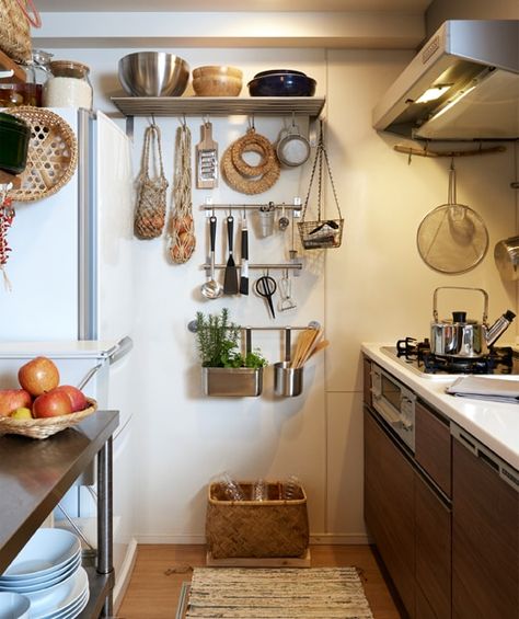 A narrow kitchen with dark cabinets and utensils hanging on metal rails and shelves on the end wall. Organiser Cucina, Kitchen Wall Storage, Narrow Kitchen, Small Kitchen Storage, Tiny Space, Dark Cabinets, Apartment Kitchen, Ikea Kitchen, Tiny Kitchen