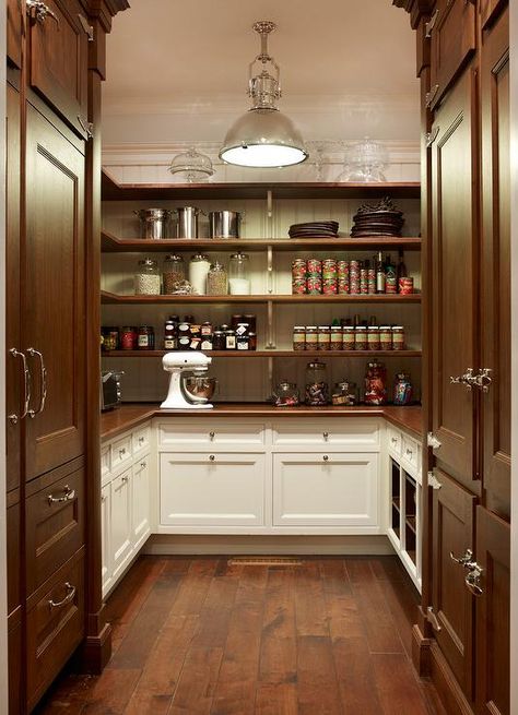 U shaped white and brown cottage kitchen pantry is lit by a Country Industrial Pendant hung over dark stained rustic wood floors accenting facing dark stained paneled refrigerators positioned on either side of white cabinets finished with a wood countertop positioned beneath beautifully organized wraparound wood shelves mounted on a beadboard trim. Brown Cottage, Kitchen Butlers Pantry, House Pantry, Pantry Inspiration, Rustic Wood Floors, Pantry Room, Pantry Remodel, Kitchen Pantry Design, Cottage Kitchens