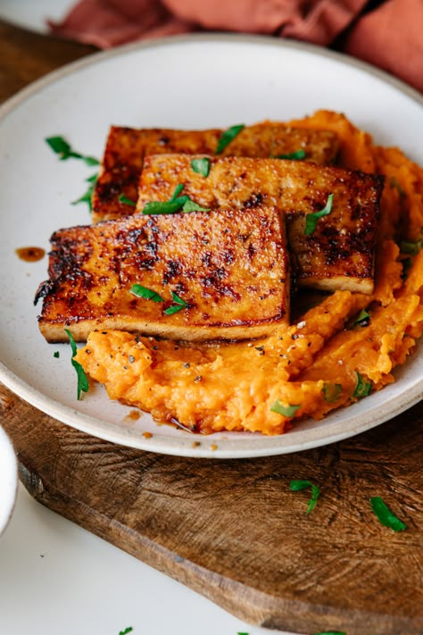 A smoky, savory tofu steak marinated before pan frying and laid on top of a bed of garlicky, herby mashed sweet potatoes. With extra umami marinade drizzled over top. The perfect 30-minute vegan dinner for weeknights! And an impressive main dish for a holiday table. Mashed Sweet Potatoes Vegan, Sweet Potato And Tofu, Tofu Thanksgiving Main Dish, Thanksgiving Tofu Marinade, Vegan Dinner With Sweet Potatoes, Tofu And Potatoes, Tofu And Mashed Potatoes, Savory Tofu Recipes, Tofu And Sweet Potato Recipes