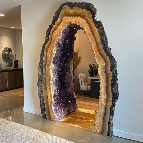 This unique doorway is designed to resemble a natural geode, with an arching, irregular frame that mimics the raw beauty of crystal formations. The outer edge features a rugged stone texture, transitioning into shimmering layers of amethyst-like crystal detailing, giving the appearance of a geode split open. As sunlight filters through, the crystals catch the light, casting subtle, colorful reflections across the entryway. The door itself is sleek and modern, contrasting beautifully with the ... Crystal Geode Decor, Geode Bedroom, Stone Door Frame, House Entrance Exterior, Exterior Steps, Concept Hotel, Sculptural Wall Art, Nature And Architecture, Architectural Ideas