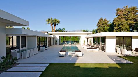 This modern backyard features plenty of seating, which includes an outdoor dining table, coordinating wicker chairs and a row of poolside lounge chairs. U Shaped House Plans, U Shaped Houses, Container Homes For Sale, Courtyard Pool, Pool House Designs, Pool House Plans, Courtyard House Plans, Building A Container Home, Modern Backyard