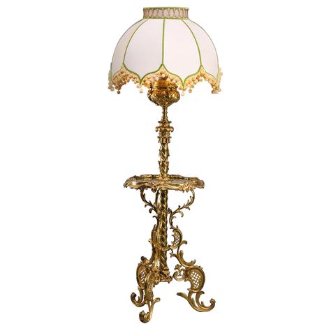 An Edwardian Gilt-Bronze Standard Lamp Tier Table. Designed in the rococo style with spirally fluted stem supporting an urn with bulb fitment above. The central tier with green onyx top. Supporting on three 'C'-scroll legs. England, Circa 1910. Fireplace Room Ideas, Standard Lamp, Fireplace Room, French Rococo, Lamp Ideas, Standard Lamps, Rococo Style, Green Onyx, Floor Lamps