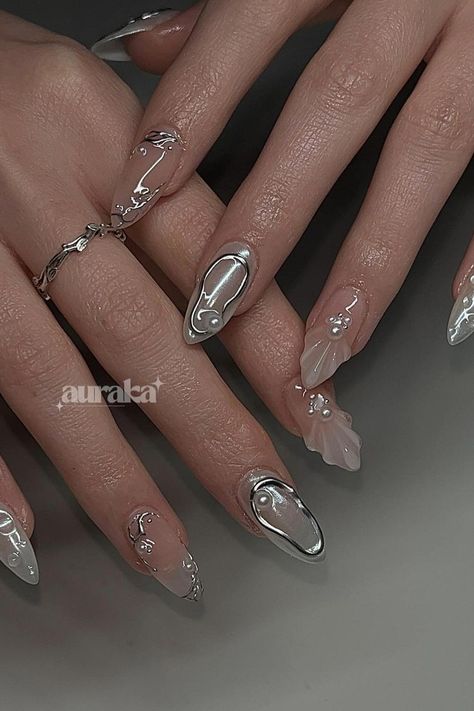 An eye-catching combination of sheen and subtlety. These stiletto nails display a lustrous metallic silver finish, complemented by clear nails with floral accents and tiny pearl embellishments. The allure of this manicure lies in its understated elegance and the contrast between the mirror-like shine and the delicate flower details. Perfect for anyone looking to add a touch of sophistication to their look. ✨  // Photo Credit: Instagram @aurakanails Firework Nails, Silver Nail Designs, Silver Nail Art, Mermaid Nails, Pretty Gel Nails, Pearl Nails, Metallic Nails, Oval Nails, Clear Nails