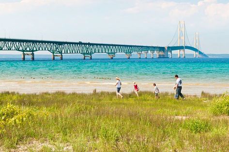 A family walks along the lake shore with the Mackinac bridge in the background; Great Lakes road trip Indiana Dunes State Park, Shasta Lake, Surf Spots, Sacramento River, Indiana Dunes, Port Huron, The Great Lakes, National Cemetery, Lake Huron