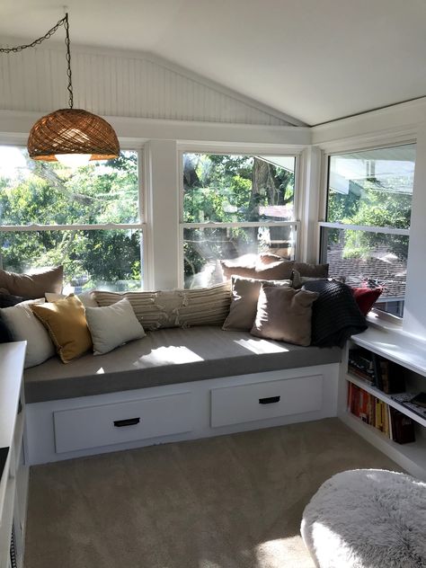 Bench with drawer storage and built-in shelves in sunroom. Wicker hanging lamp thrifted from a vintage store. Built In Bench Seating Sunroom, Built In Bench Sunroom, Built In Benches With Storage, Couch In Sunroom, Sunroom Bench Seating, Sunroom Built In Seating, Sunroom With Built In Benches, Window Seat Sunroom, Conservatory Storage Ideas