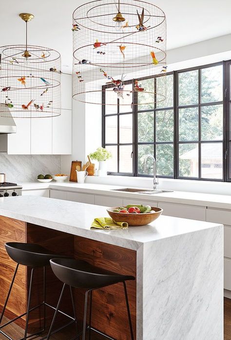 In this kitchen, cage-like pendants get an added touch of whimsey with the addition of faux birds. The see-through mesh also doesn’t block the views outside, where the real birds hang out. | Photographer: Valerie Wilcox | Designer: Stephanie Pellatt, Pivot Design Group; Leanne Tammaro & Adolphina Karachok, Designtheory Feature Lights, Narrow Kitchen Island, Whimsical Kitchen, Walnut Kitchen, Pantry Wall, Narrow Kitchen, Walnut Cabinets, Kitchen Remodel Design, White Oak Floors