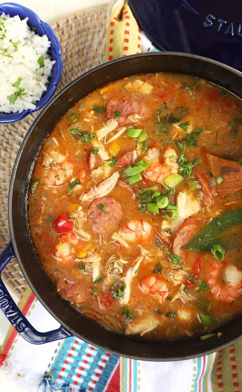 Overhead shot of seafood gumbo in a dark blue pot with a blue bowl filled with rice on a white background. Seafood Gumbo Recipe Easy Simple, Fish Gumbo Recipe, Seafood Recipes Easy, Easy Gumbo Recipe Simple, Seafood Gumbo Recipe Louisiana, Easy Seafood Gumbo, Seafood Gumbo Recipe Easy, Shrimp Gumbo Recipe, Easy Gumbo