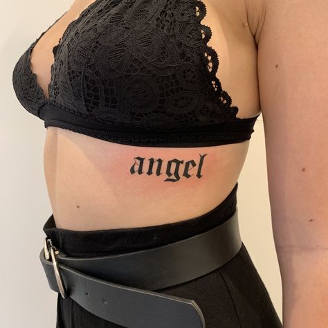 Angel Old English Tattoo, Angel Tattoo Letters, Angel Word Tattoo For Women, Angel Tattoo Ribs, Word Angel Tattoo, Gothic Writing Tattoo, Angel Tattoo Writing, Angel Lettering Tattoo, Angel Writing Tattoo