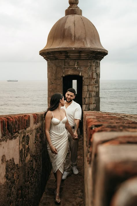 woman in white dress holding hand and leading him forward out of a Spanish fort. Engagement Photos Mission San Juan, San Juan Photoshoot, San Juan Engagement Photos, Latino Engagement Photos, St Augustine Florida Engagement Photos, Engagement Photos Puerto Rico, Spanish Style Engagement Photos, Old San Juan Engagement Photos, Old San Juan Photoshoot