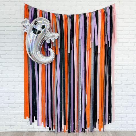 Set the stage for a spooktacular Halloween with our Halloween Fringe Backdrop. This vibrant backdrop features a mix of orange, gray, lavender, pink, and black fringe, adding a pop of color to your spooky celebrations. Available in a variety of sizes, it's perfect for photo booths and party decorations. Get ready to have some frightfully fun moments captured against this eye-catching backdrop. Colors: Orange, Gray, Pink, Lavender and Black Three sizes to choose from:  backdrop is approximately 7' in height and 4', 5', 6', 7' or 8' wide with extra rope on each side.  Our backdrops are weather-resistant, light-weight, and reusable for indoor and outdoor use. Easy to hang: You just need to unroll, tie a loop with the string and hang! We recommend using reusable command hooks to secure. **Due t Diy Backdrop Halloween, School Halloween Photo Backdrop, Halloween Streamer Backdrop, Halloween Party Backdrop Photo Booths, Rainbow Halloween Decor, Halloween Photo Backdrop Diy, Fringe Streamer Backdrop, Halloween Event Decor, Halloween Backdrop Ideas