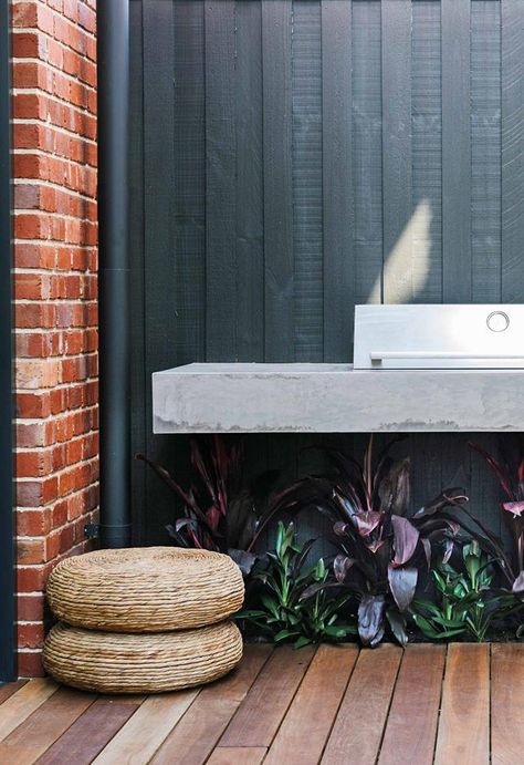 An outdoor kitchen with a barbecue creates a walkway between the house and the studio apartment. The palette of concrete, red brick and black wood continues inside. Brick House Extension, Red Brick And Wood Exterior, Red Brick House Deck Color, Red Brick House With Deck, Red Brick And Black Exterior, Brick And Black Exterior, Cladded Bungalow Exterior, Brick And Wood Exterior, Black Timber Extension