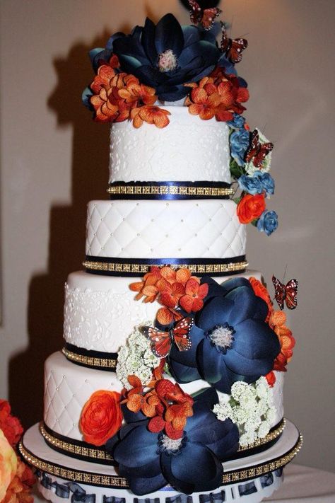 Silk flowers adorn this 4 tier wedding cake.....burnt orange and navy blue were the main colors of the wedding party Burnt Orange And Navy Blue Traditional Wedding, Burt Orange And Navy Blue Wedding, Navy And Orange Wedding Cake, Navy Blue And Burnt Orange Wedding Cake, Orange And Blue Wedding Cake, Burnt Orange Navy Blue Wedding, Orange Wedding Cake Ideas, Burnt Orange And Blue Wedding, Navy And Burnt Orange Wedding