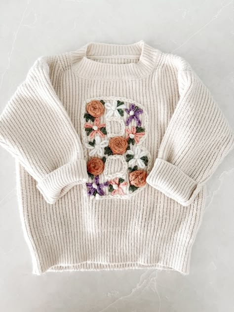 These fully customizable hand embroidered letter sweaters are sure to be the perfect gift or addition to any of the sweet littles in your life. Perfect for baby showers, name announcements, milestones, birthdays, and more. Sweaters are made of a chunky knit with a more oversized/relaxed fit. Great for spring, fall, and winter. Choose the color and size of the sweater you would like, some sweater sizes may vary based on color. Fill in the personalization box with the letter and flower colors. --- Hand Stitch Name On Sweater, Embroidered Baby Sweater, Embroidery Sweaters, Hand Embroidered Sweater, Baby Jumpers, Clothes Embroidery Diy, Personalized Sweater, Flower Colors, Embroidery Sweater