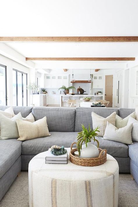 A round ivory ottoman coffee table sits on a gray rug in front of a blue-gray u-shaped sectional accented with ivory pillows. Pure Salt Interiors, Pure Salt, Ottoman Decor, Apartment Decoration, Grey Sectional, Cottage Living Rooms, Ottoman Coffee, U Shaped Sectional, Coastal Living Room