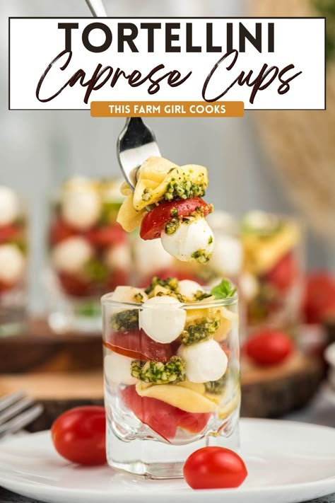 These Tortellini Caprese Salad Cups are the perfect way to add a fresh, summery salad to your potluck rotation! It's a simple recipe to make and are full of delicious flavors. We're talking ripe tomatoes, bright pesto sauce,  mozzarella cheese and cheesy tortellini pasta. #caprese #summersalad #tomatomozzarella Pasta Salad Appetizer Cups, Caprese Salad Cups, Pasta Salad In Cups, Pasta Salad Cups For Party, Pasta Salad Cups, Salad Cups For Party, Caprese Tortellini Salad, Caprese Cups, Tortellini Caprese Salad