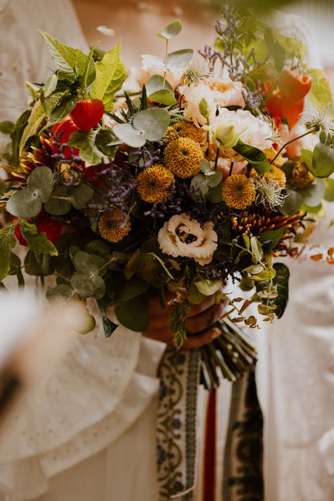 Colourful orange and yellow wedding bouquet with foliage decorated with patterned ribbon for vinatge 70s inspired wedding | wedding flowers | bridal bouquet | The Portfolio People Green And Mustard Wedding, Earthy Bouquet, Velvet Queen Sunflower, 70s Inspired Wedding, Yellow Wedding Bouquet, 70s Wedding, Wedding Bouquet Preservation, Summer Wedding Bouquets, Rustic Wedding Bouquet