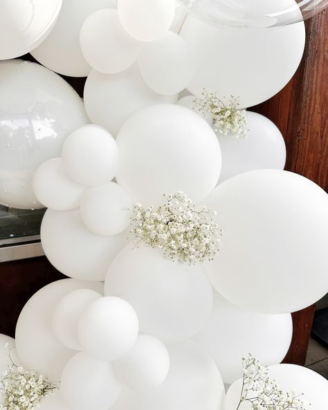 Elegant. Clean. Timeless. With hand-placed pearl details and traditional florals, this garland was custom made to celebrate a wedding rehearsal dinner. Thank you for choosing It’s Your Day to be part of your life milestones and celebrations. 🤍 - - - - - #itsyourday #balloons #balloonartist #balloongarland #customballoons #grabandgoballoons #birthdayballoons #balloonideas #creativeballoons #balloonstylist #quality #service #smallbusiness #wedding #weddingrehearsal #weddingballoons #wedding... All White Balloon Garland With Flowers, White Balloon Arch With Flowers, White Bridal Shower Balloon Arch, White Flower Wall With Balloons, Pearl White Balloons, White Bride Balloons, Custom Balloons, White Balloons, Balloon Columns