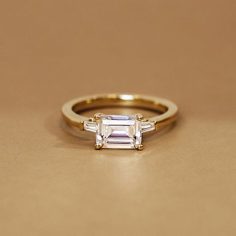 Emerald Cut East West Tapered Baguette Diamond Engagement Ring - 18K Yellow Gold. This modern ring takes a classic silhouette and elevates it with the addition of east west set tapered baguette diamonds that shine brightly, making this style the perfect choice for anyone looking for a three stone ring with a twist (1/5 total carat weight). Rectangle Engagement Rings, Brilliant Earth Rings, Cute Engagement Rings, Future Engagement Rings, Agate Engagement Ring, Baguette Diamond Rings, Emerald Cut Rings, Three Stone Ring, Emerald Engagement Ring Cut