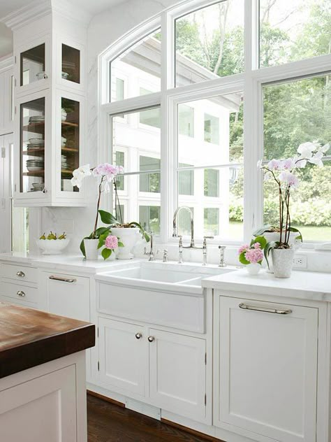 Stunning kitchen design with arched window, creamy white kitchen cabinets with marble countertops, wood panel dishwashers flanking farmhouse sink, marble slab backsplash, polished nickel Perrin & Rowe Bridge Faucet, orchids and white kitchen island with butcher block countertop.. Dream Kitchens Design, Kitchen Farmhouse, White Kitchen Cabinets, Farmhouse Sink, Kitchen Window, White Cabinets, Beautiful Kitchens, 인테리어 디자인, Dream Kitchen