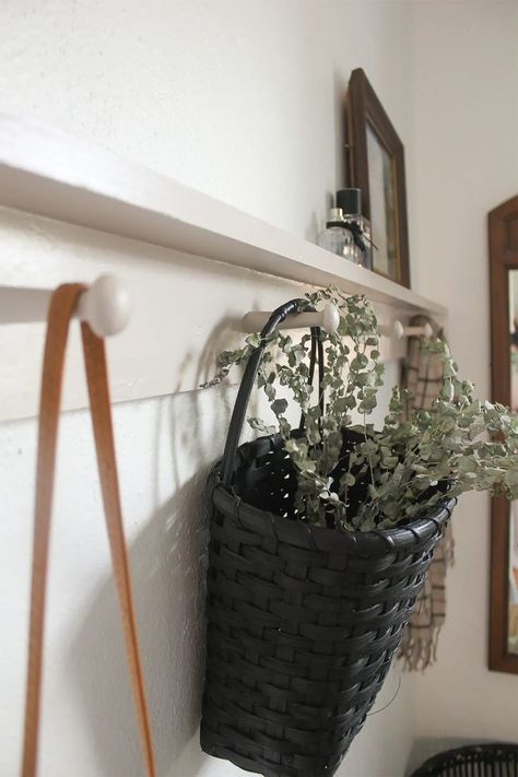 Stylish white DIY peg rail shelf with attached to white wall with purse, basket and scarf hanging from it. A modern style shaker peg rail with simple decorations. Picture frame and perfume bottles on top of shelf. Diy Peg Rail, Popcorn Paint, Peg Rail Shelf, Shaker Peg Rail, Peg Shelf, Awkward Corner, Rail Shelf, How To Make Floating Shelves, Fresh Popcorn