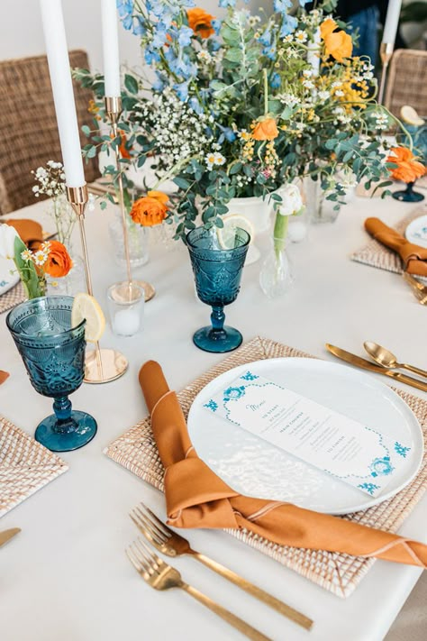 Blue and Rust Dinner Party Table Setting Green Orange Blue Wedding, Blue And Orange Wedding Table, Colorful Glassware Wedding, Light Blue And Orange Wedding, Blue And Orange Wedding Theme, Orange And Blue Wedding Colors, Orange Blue Wedding, Seaside Wedding Decor, Orange And Blue Wedding