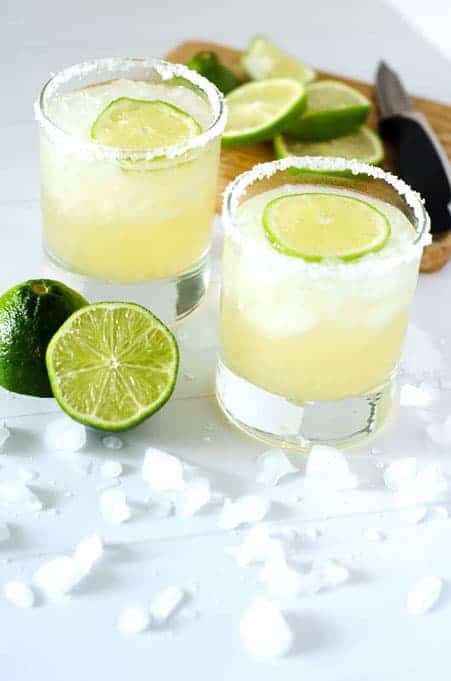 two glasses of paleo margaritas on the rocks surrounded by limes and ice Wine Drinks Recipes, Paleo Margarita, Original Margarita Recipe, Lemon Lime Margarita, Top Shelf Margarita, Key Lime Margarita, Lime Margarita Recipe, Classic Margarita Recipe, Traditional Margarita