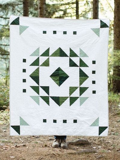 The Evergreen Quilt Pattern showcases a modern ombre design that pops against a crisp white background. Deceptively easy and versatile, the multi-sized quilt pattern uses half-square triangles for the center block and builds on it with stripes to com... Green And White Quilts Ideas, Modern Simple Quilt Patterns, Sage Green Quilt Patterns, Green And White Quilt, Green Quilts Ideas, Evergreen Quilt, Neutral Quilts Ideas, Geometric Quilt Patterns, Simple Quilt Patterns