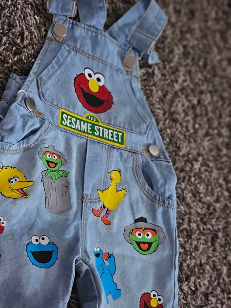 Sesame street overalls. Can be customized as birthday overalls by adding a number to them ad no additional cost! Available in both shorts and pants overalls. please specify which you would prefer. Sesame Street Birthday Overalls, Custom Sesame Street Outfit, Sesame Street Theme Birthday Party, Elmo Theme Party, Sesame Street Overalls, First Birthday Elmo Theme, Sesame Street Birthday Theme, Elmo Birthday Outfit Boy, Sesame Street Shoes