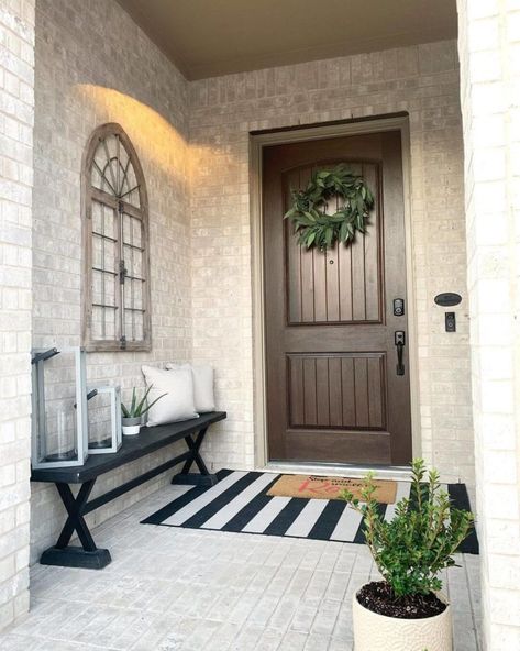 When a porch is small, scale is important when selecting furniture. This front porch has a narrow black bench which does not overwhelm the space. Small Outside Entryway Ideas, Small Front Door Decor Entrance Modern, Long Front Entryway Ideas Exterior, Small Front Entrance Ideas Outdoor, Small Front Door Porch Ideas, Small Outdoor Entrance Ideas, Double Door Front Porch Decor, Small Front Porch Bench Ideas, Front Outdoor Entrance Ideas