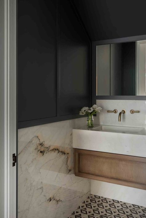 Bathroom with geometric tile, navy blue wainscoting and marble walls