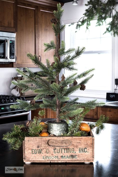 A little faux pine tree tucked into a vintage crate tree skirt makes the cutest Christmas vignette! See this plus other Christmas kitchen decorating ideas in this post! Wooden Crate Fireplace Decor, Christmas Wooden Crate Decor, Christmas Tree In Box Crates, Crock Christmas Tree, Wood Crate Christmas Decor, Christmas Kitchen Decorations Ideas, Kitchen Vignettes Decorating Ideas, Wooden Box Centerpiece Christmas, Wooden Crate Christmas Decor