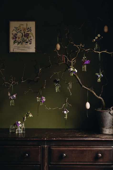 My mother’s exquisitely embroidered canvas of spring flowers was the inspiration for this miniature hanging garden display. I chose a horizontal branch of red twisted corkscrew hazel, festooned with beautiful maroon catkins, to complement the verticality of hanging bottles filled with spring garden flowers, and a clutch of wooden eggs to create a perfect Easter arrangement.  📸 Eva Nemeth ✏️ Jacky Mills Branch Display, Corkscrew Hazel, Hanging Bottles, Gardens Illustrated, Spring Gardens, Easter Arrangement, Spring Garden Flowers, Garden Display, Embroidered Canvas