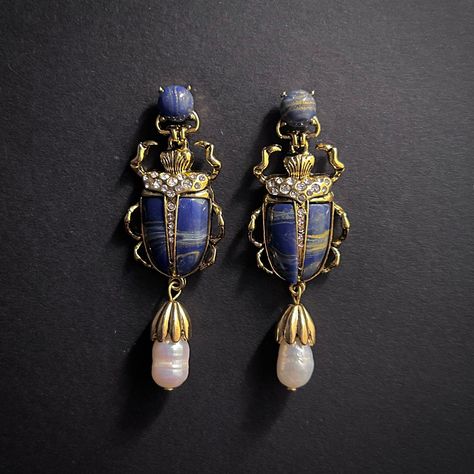 Description Absolutely gorgeous Art Deco style statement earrings with rows of sparkling rhinestones and blue lapis lazuli stone in scarab shaped 18K gold plated settings, completed by snow white baroque faux pearls dangling under. ✔ Stud fastening with sterling silver ear posts✔ 18K gold plating✔ Length 6 cm/2.4 inches✔ Materials: 18K gold plating, 925 sterling silver, faux pearl, lapis lazuli stone, rhinestones Shipping • Free shipping worldwide• Tracking included• EUROPE: approx. 4-7 business Nordic Noir, Artistic Earrings, Bijoux Art Nouveau, Lapis Lazuli Blue, Jewelry Styles, Insect Jewelry, Lapis Lazuli Stone, Treasure Box, Art Objects