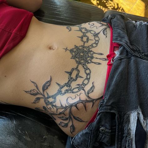 Lower stomach ornamental chain botanical tattoo Ornamental Lower Stomach Tattoo, Woman Lower Stomach Tattoo, Tattoo Lower Stomach, Stomach Tattoos Plants, Women’s Lower Stomach Tattoo, Plant Stomach Tattoo, Symmetrical Stomach Tattoo, Lower Abdomen Tattoo Women, Tattoo Positions