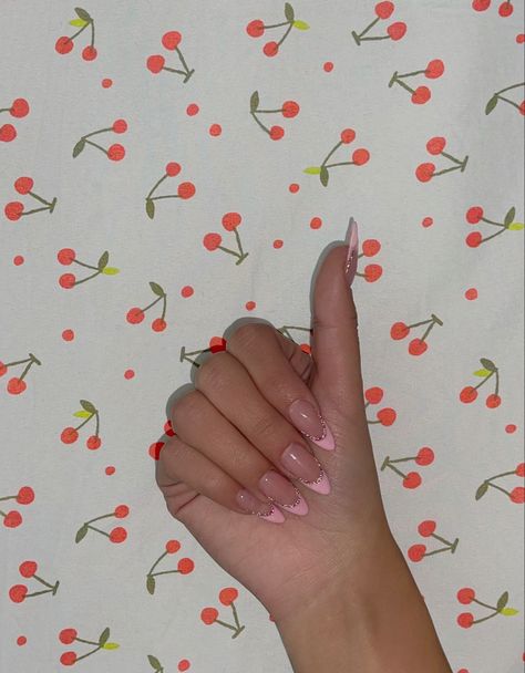 hand in fist to show pink french tips almond acrylic nails with sparkle outline, taken in front of cherry sheets Sparkle Almond French Tip Nails, Pink French Tip Nails Almond With Pearls, Pink French Tip With Glitter Outline, Almond French Tip Nails With Design Pink, Pink French Tip With Glitter Line Almond, Almond Pink Glitter French Tip Nails, Pink Glitter French Tips Almond, French Tips With Glitter Outline, Pink French Top Almond Nails