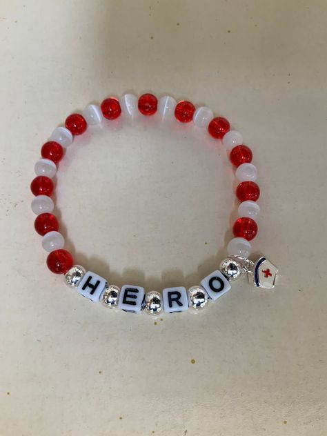 Support your favorite nurse with this adorable HERO bracelet. Made with glass red and white beads, and plastic letters surrounded by silver beads. There is a small enamel nurse's cap charm hanging from the side.   It stretches to fits up to a 7.5" wrist.  Comes wrapped in a gift giving bag with tie. In stock items ship within 2-3 business days.  Custom orders can take up to 10 days. Shipping Times - Please allow 3-5  delivery in the U.S.  7-10 business days to Canada and 10-15 business days to E Hero Bracelet, I Am A Hero, Nurse Bracelet, Hero Nurse, Bracelet Business, Nurse Jewelry, Beaded Charm Bracelet, Red Beaded Bracelet, Plastic Letters