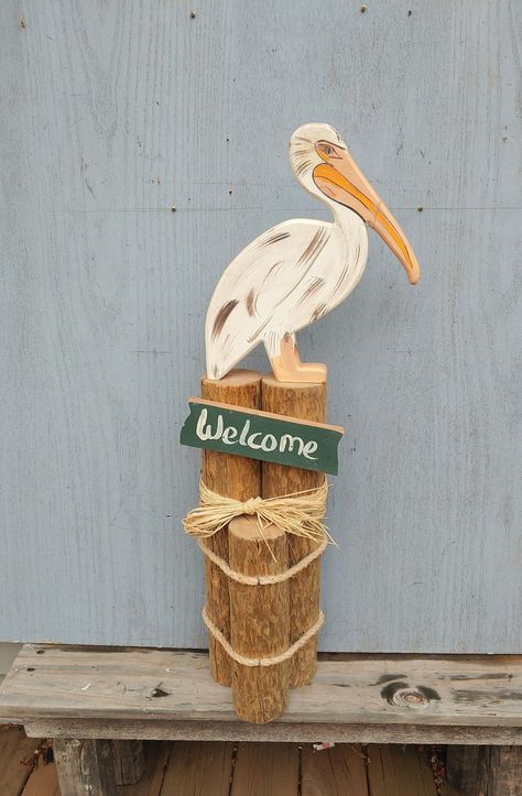 "Vintage Pelican On Pier Posts, Waterfront Decor, Seaside, Lakeside, Waterfowl, Bird, Wood, Ocean, Welcome Sign  \"VINTAGE WOOD PAINTED PELICAN ON 3 PIER POSTS LASHED TOGETHER\" Here is a cute welcome sign for your dock or seaside home.  A wood pelican is sitting on 3 pie posts that are lashed together with rope.  The pelican was cut in 2 pieces with the beak added to complete it.  It is not broken there, it is put together there.  1016 Measures 12\" Wide by 33\" High by 6 1/2\" Deep. Zoom into Primitive Beach Decor, Pelican Decor, Breaker Rock Beach Vbs 2024 Decorations, Bay Decoration, Beach Welcome Sign, Painted Pelican, Caribbean Decor, Ocean Vintage, Vintage Wood Signs