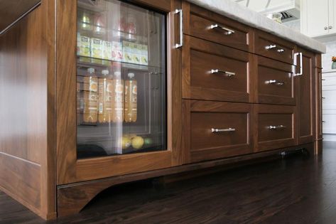 A gorgeous walnut stained island fitted with drawers donning polished nickel pulls and a glass front mini fridge fixed beneath an Iceberg Quartzite countertop. Stained Island, Dark Stained Wood Floors, Walnut Butcher Block Countertops, Bone Inlay Dresser, Fridge Design, Leaded Glass Door, Door Design Photos, Beverage Fridge, Stained Doors