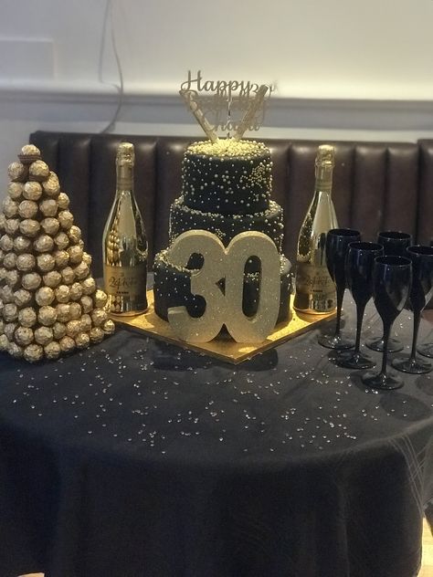 Cake table with gold champagne bottles, black champagne flutes and ferrero rocher tree! 40th Bday Dessert Table, Black And Gold Cake Table, Gold Cake Table, Ferrero Rocher Tree, Black Champagne Flutes, Gold Table Centerpieces, Black And Gold Birthday Cake, Gold Candy Buffet, Cake Table Decorations Birthday