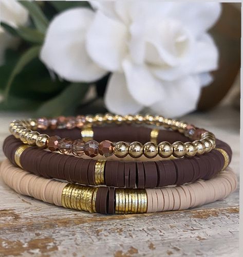 This is a chic stack of 3 Heishi bracelets... one neutral with light gold spacers and a section of brown  Heishi, and a  brown with light gold spacers and a 4mm gold ball bracelet with beautiful bronze / brown crystals. Such a gorgeous stack!  gold filled beads  Sizes are small 6.5 Medium 7  Large 7.5  - if you need smaller or larger please let me know!  Please keep out of water, no chemicals, bathing or swimming with them on. Brown Bead Bracelet Ideas, Gold Ball Bracelet, Brown Crystals, Heishi Bracelets, Stacked Beaded Bracelets, Brown Bracelet, Clay Bracelet, Bracelets Diy, Ball Bracelet