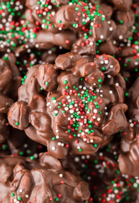 A close up of a peanut and chocolate cluster with sprinkles. Crockpot Christmas Candy, Crock Pot Candy, Crockpot Candy Recipes, Crockpot Christmas, Chocolate Peanut Clusters, Christmas Candy Homemade, Crockpot Candy, Peanut Clusters, Christmas Sweet Treats