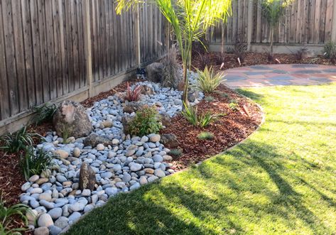 River rocks and mulch can combine to make really gorgeous designs for your landscaping. By mixing materials you can create a more aesthetic, textured look! Visit us today!  #TheOriginalLandscapeSupply #ChapinLandscape Garden With Rocks, Low Water Landscaping, Rustic Outdoor Decor, Mulch Landscaping, Low Water Gardening, River Rock Landscaping, Rock Landscaping, Place Making, Low Maintenance Garden