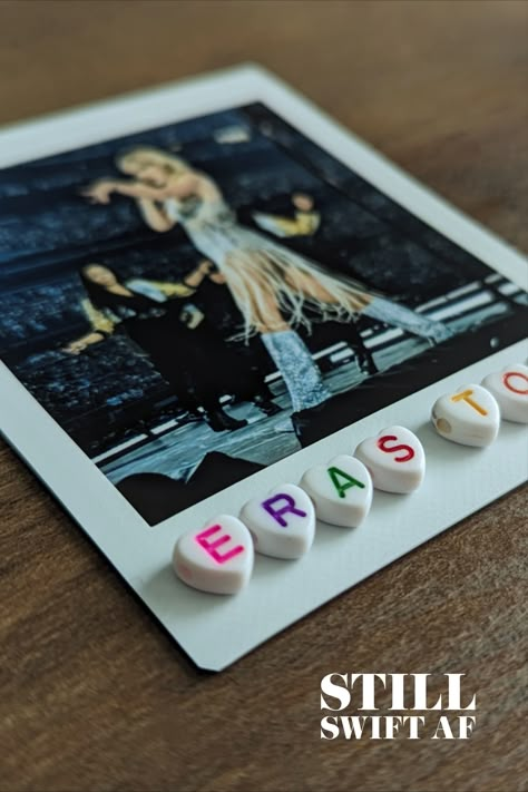 Image of a polaroid photo of Taylor Swift singing with white heart beads below that say, 'ERAS TOUR' in various colors. Taylor Swift Memory Box Ideas, Taylor Swift Shadow Box Ideas, Eras Tour Memory Frame, Concert Shadow Box Ideas, Eras Tour Shadow Box Ideas, Eras Tour Scrapbook, Swiftie Gifts, Girls Valentines Boxes, Taylor Swift Tickets