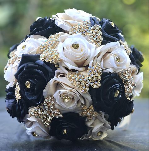 Beautiful champagne and black  flower bouquet decorated with gold flower and butterfly broches.  Perfect for your Quinceañera, Sweet 16, and Wedding.  Usually takes 1-2 weeks to be shipped. However if you need fast delivery, let us know.  Thank you Black White And Gold Flower Bouquet, Quince Decorations Black And Gold, Solangelo Wedding, Black And Gold Quinceanera Theme, Black And Gold Sweet 16, Mascarade Wedding, Black Flower Bouquet, Broche Bouquet, Gold Quinceanera Theme