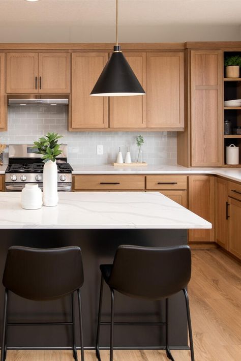 It’s our favorite time of the year! The Spring #ParadeofHomesTC is on now through April 7. 🌷☀️ 🌈  __ Oak cabinets, black kitchen island with black barstools, floating pendants, white countertops, kitchen goals, light wood floors. White Cabinets Wood Island Black Counter, Light Wood Cabinets With Black Island, Black Island Oak Cabinets, Kitchen Wood Cabinets Black Countertop, Black Kitchen Island Wood Cabinets, Honey Oak Cabinets Black Countertop, Oak Cabinets Black Island, Light Wood And Black Kitchen, Natural Wood And Black Kitchen