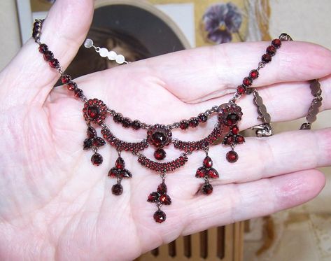 Dating to the late 1800s or so may I offer this breathtakingly beautiful Bohemian Garnet (points up) necklace from the Victorian era. With a wonderful festoon appearance, the metal of the necklace is thick with pale 9K rose gold (aka garnet gold - tested, not marked) - possibly over brass but I have the feeling the gold may be over silver. This is just a gut instinct which may or may not be right but I have not had a necklace like this with so much of a gold backing in a long, long time. Tongue-in clasp closure that works as it should. Neck length is 15-1/2"; center drop measures 1-1/2". Weight is 16.5 grams - quite a nice weight. Condition is excellent with no stones missing. I can spot perhaps (maybe) 2 replacements but again, I may be wrong on this. The back rose gold has mellowed quite Vintage Jewelry Necklaces, Gut Instinct, Victorian Style Jewelry, Festoon Necklace, Garnet And Gold, Fancy Necklace, Vintage Jewelry Necklace, Dope Jewelry, Pretty Necklaces